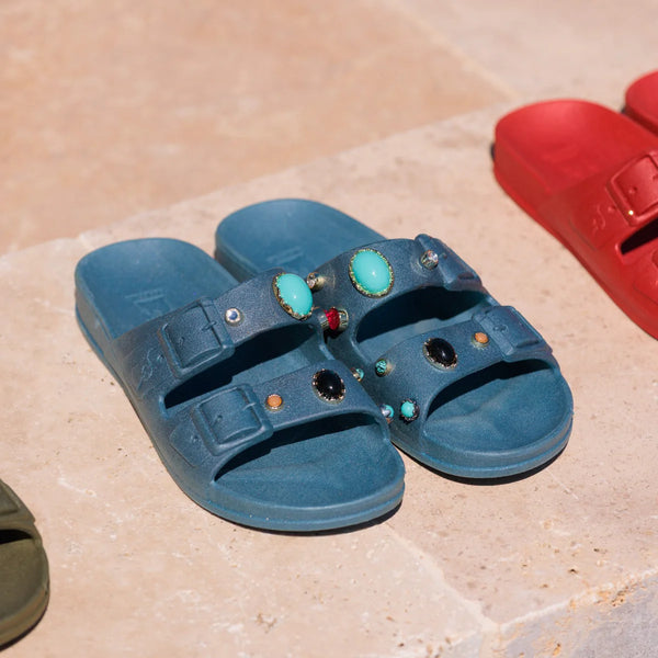 Blue sandals with gemstones on a stone surface