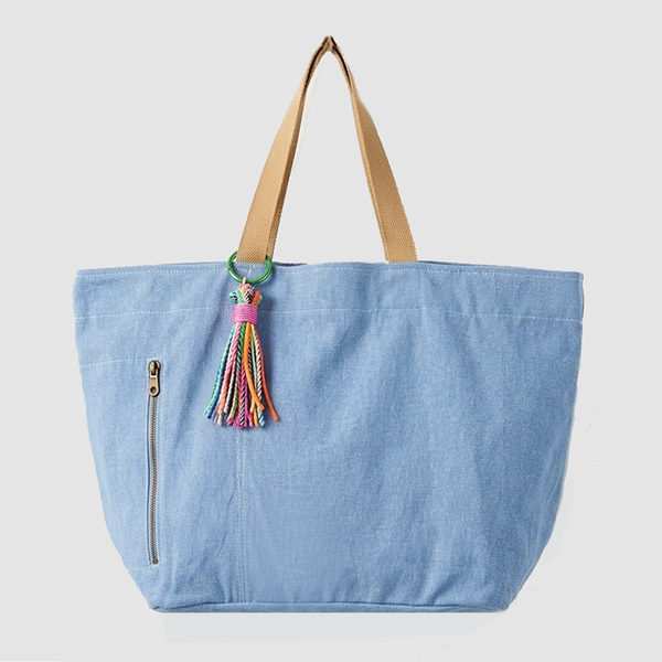 Blue tote bag with a colorful tassel on a light gray background
