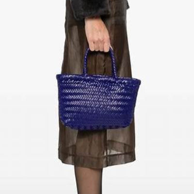 Person holding a blue woven handbag against a white background
