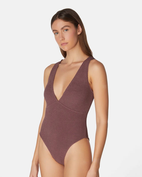 Woman wearing a brown ribbed swimsuit on a white background