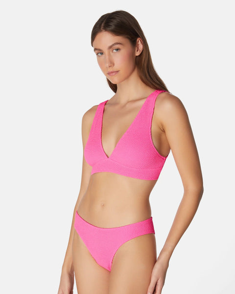 Woman wearing a bright pink bikini set on a white background