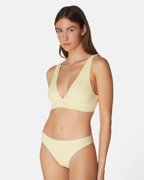 Woman wearing a light yellow bikini set on a white background