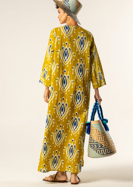 Woman wearing a yellow patterned dress with a matching hat and bag on a white background
